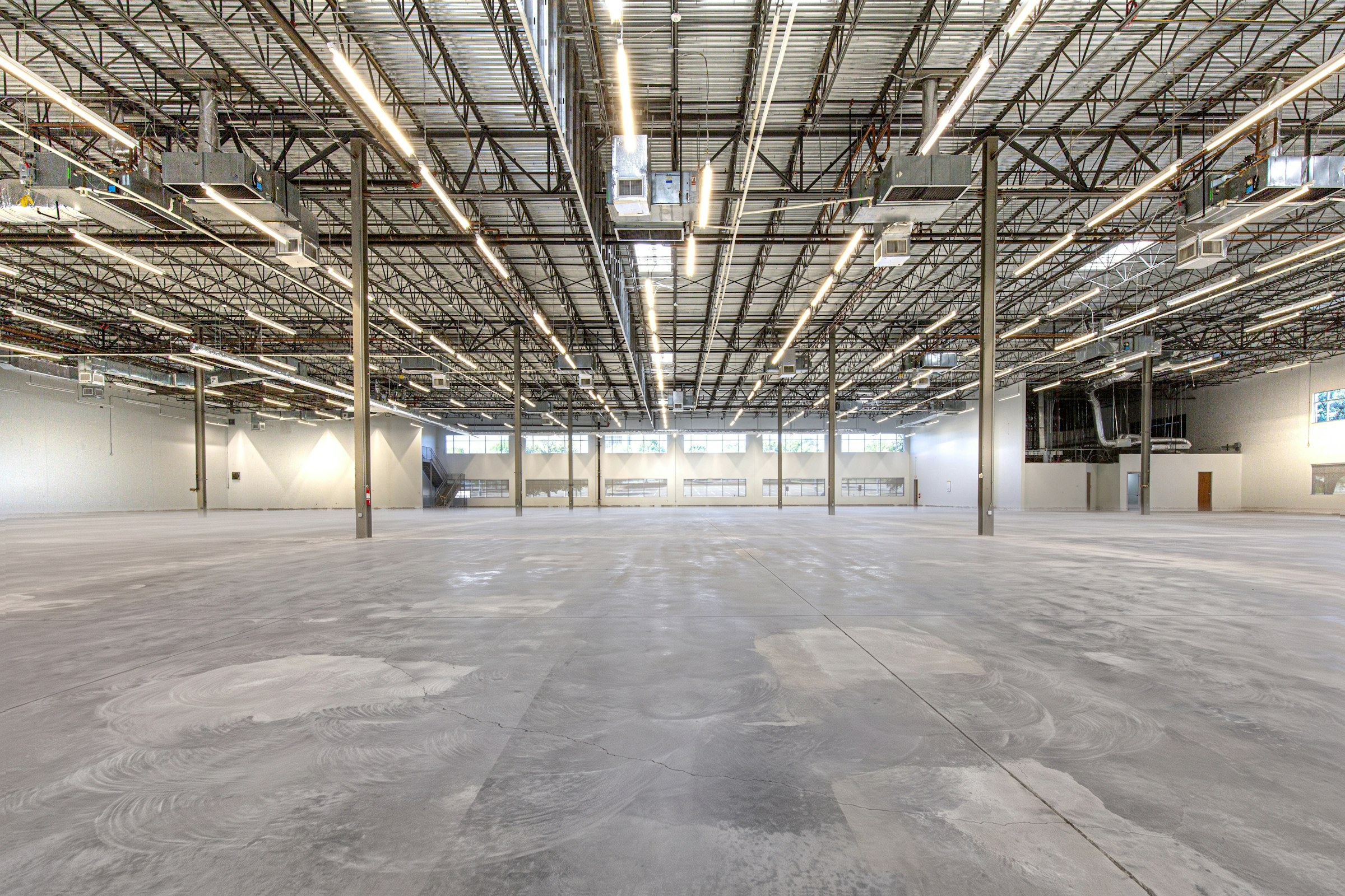 The same warehouse before coating: bare, diamond-ground concrete with grinder swirls and hairline cracks